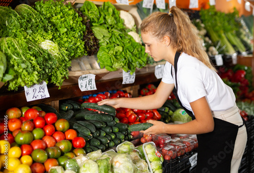 Fotografie Focused fifteen-year-old girl who works part-time in a store as a trainee salesw