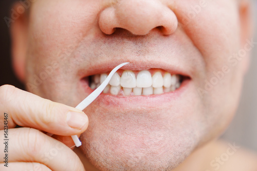 a man s mouth close-up. a man brush your teeth plastic toothpick with dental floss. concept of hygiene and health of teeth and oral cavity. daily care and brushing of teeth.