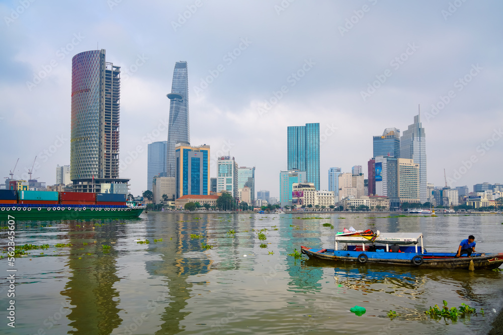 Fototapeta premium Hochiminh, Vietnam JAN 14 2023: Early morning in District 2 looking over District 1, seeing bitexco tower, IFC One building, cargo ships moving on the Saigon River