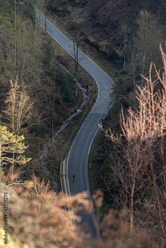 A cyclist going down hill on a curvy mountain road at the countryside