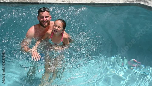father and child putting their heads under water in a swimming pool