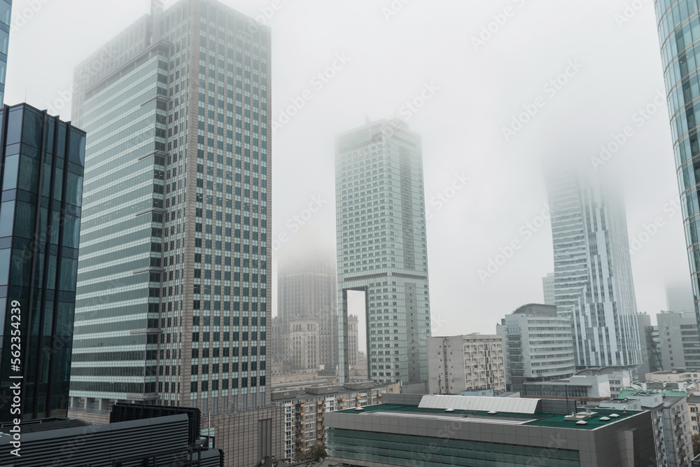 Fototapeta premium Beautiful modern European city of Warsaw, Poland with office and business buildings with fog on a cloudy day. Urban wallpaper, concept