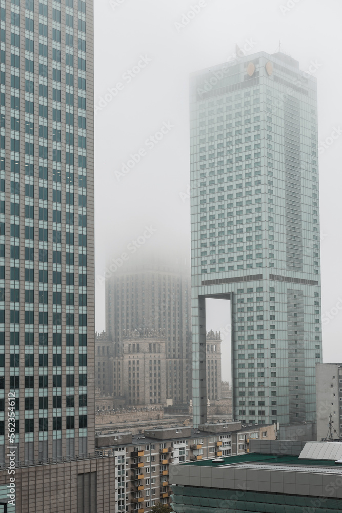 Obraz premium Beautiful modern foggy European city of Warsaw with office skyscrapers, business centers and a palace of culture with a fog. Urban cloudy day