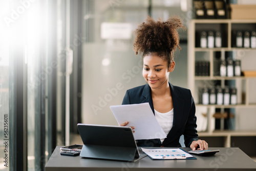 Young beautiful woman typing on tablet and laptop while sitting at the working table office