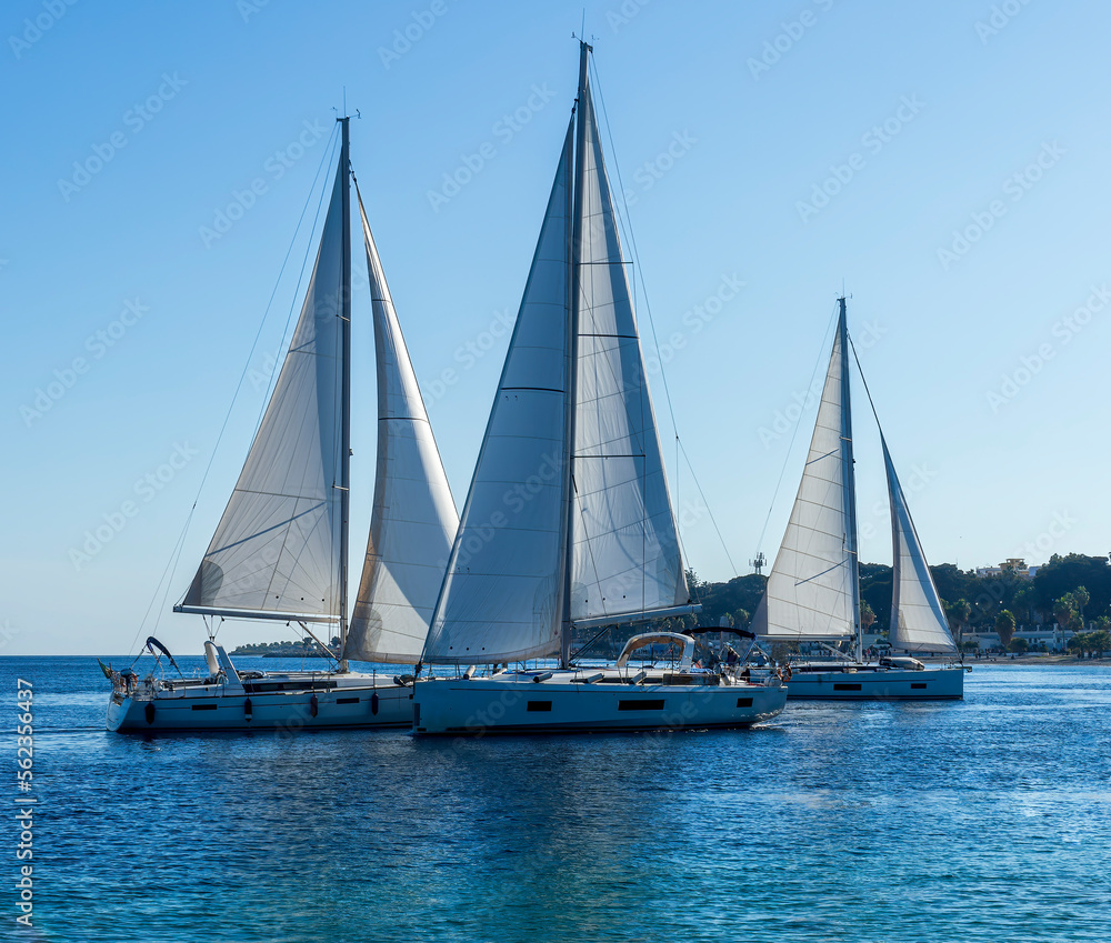 sailing yacht boats with white sails in blue sea , seascape of beautiful ships in sea gulf with mountain coast on background