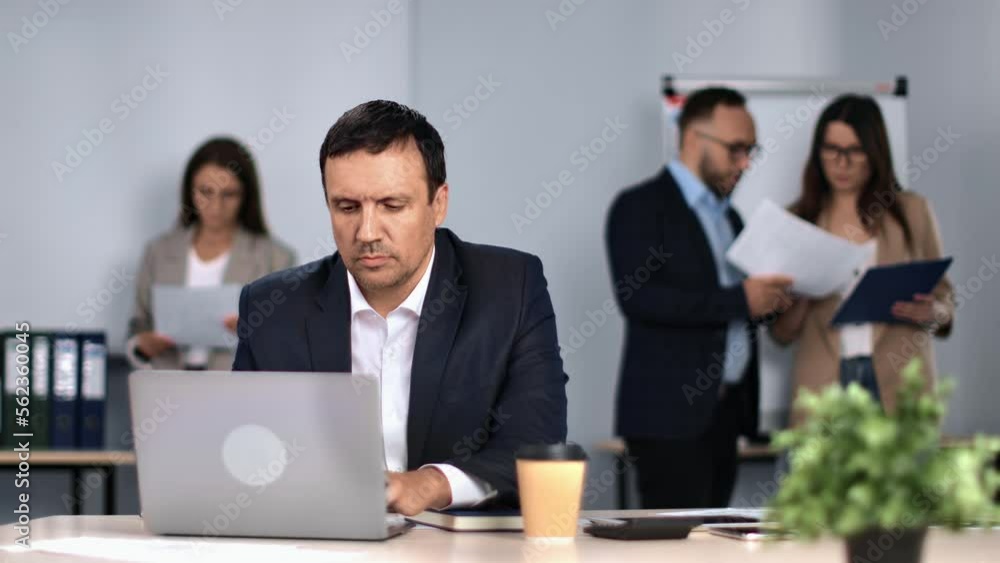 Office routine workspace with colleagues man working laptop desk coworkers discussing job corporate Office routine workspace with colleagues man working laptop desk coworkers discussing job corporate