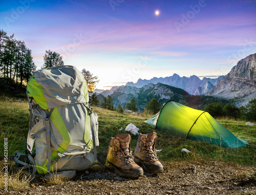 Hiking Equipment, Tent, Backpack and Boots under a moon night sky at amazing twilight hour. Alps, Triglav National Park, Slovenia. photo