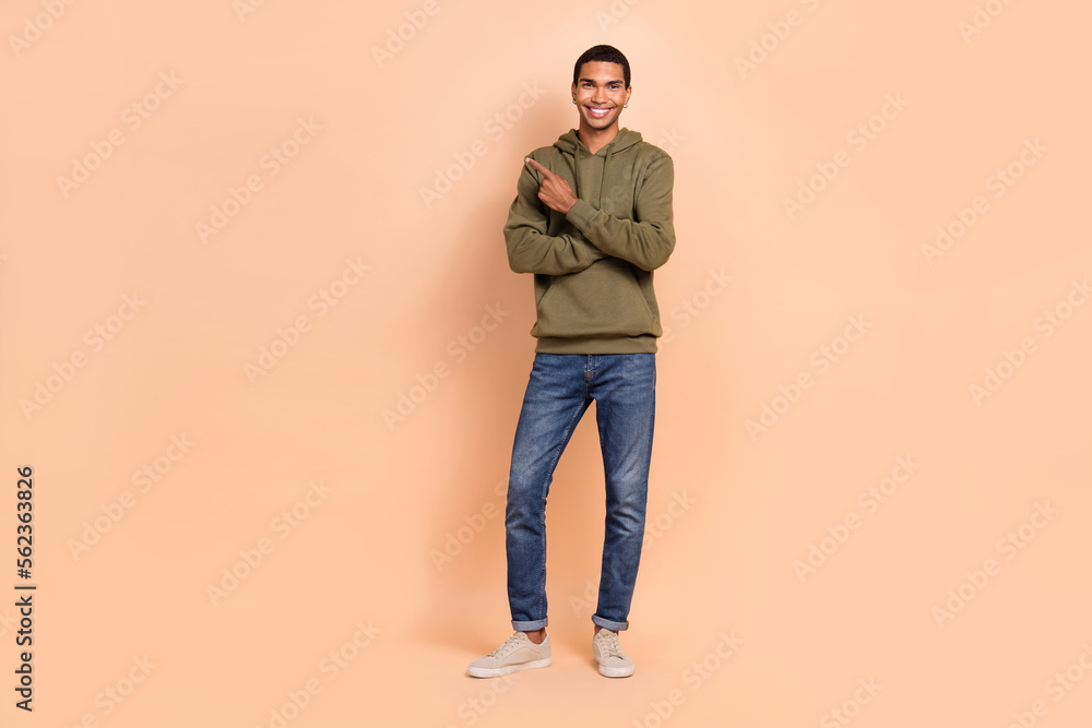 Fototapeta premium Full length photo of attractive joyful man wear khaki clothes arm direct empty space positive feedback isolated on beige color background