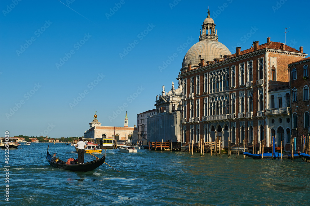 View of a gondolier rowing on his gondola in the Venetian Grand Canal with Basilica of Our Lady of Health on your right