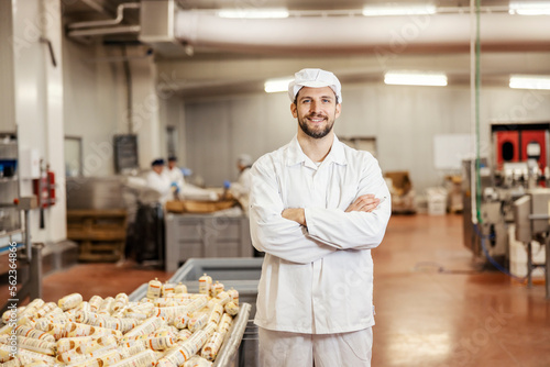 A happy meat industry worker is standing next to a container full of meat products and smiling at the camera.