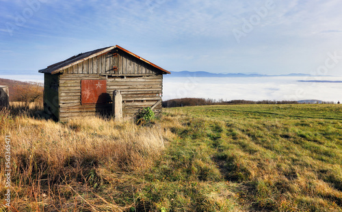 Old hut over clouds in pasture mountain landscape.