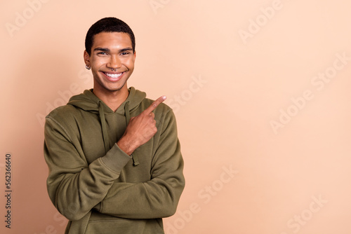 Photo of confident cheerful man wear green khaki sweatshirt pointing finger empty space isolated beige color background