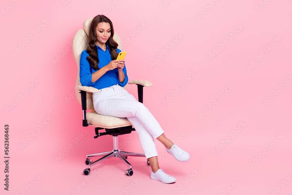 Full body size photo of director business lady sit her new comfortable office chair use phone browsing telegram isolated on pink color background Full body size photo of director business lady sit her new comfortable office chair use phone browsing telegram isolated on pink color background
