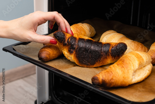 a man takes a burnt croissant out of the oven photo