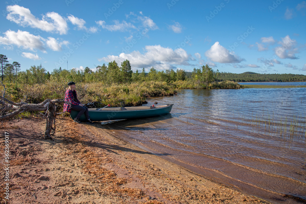 Woman and canoe on the lake beach