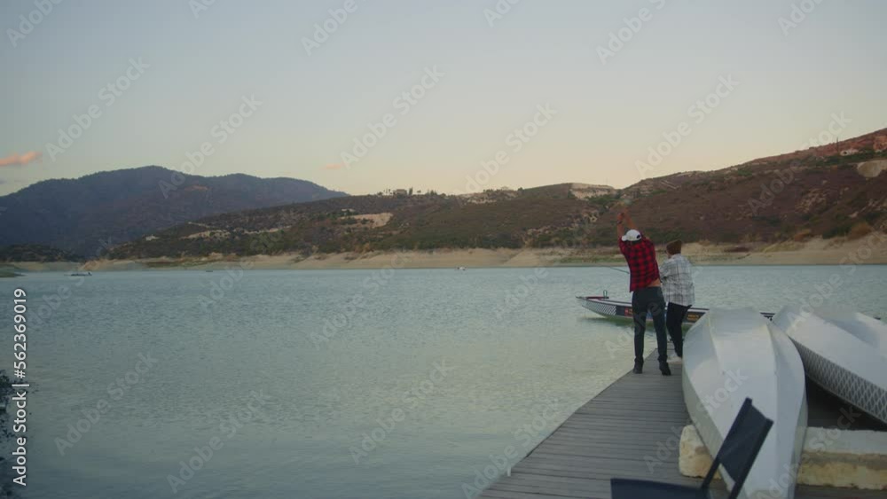 Hipster men fishing and casting fishing rods in water Hipster men fishing and casting fishing rods in water
