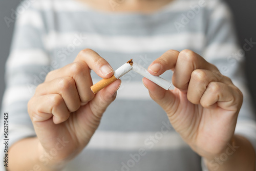 Close up young woman holding broken cigarette in hands. Happy female quitting refusing smoking cigarettes. Quit bad habit  Stop smoking cigarettes  health care concept. No smoking campaign.