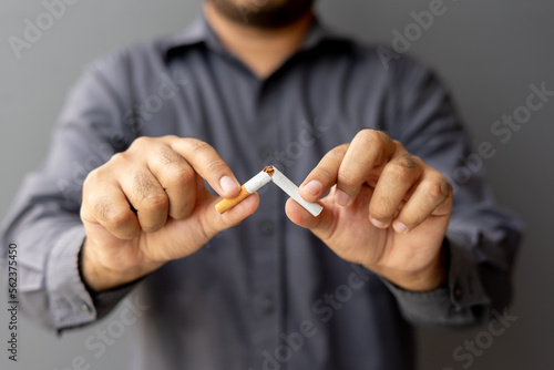 Portrait young man holding broken cigarette in hands. Happy male quitting refusing smoking cigarettes. Quit bad habit, Stop smoking cigarettes, health care concept. No smoking campaign.