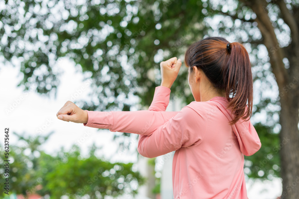 Young asian woman relaxing in sports outfits pink stretching before workout in the park get a healthy lifestyle at sunset. Healthy sporty girl warming and stretching arms and looking away. Young asian woman relaxing in sports outfits pink stretching before workout in the park get a healthy lifestyle at sunset. Healthy sporty girl warming and stretching arms and looking away.