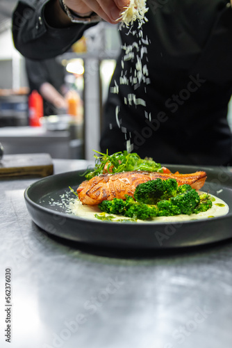 Fototapeta Naklejka Na Ścianę i Meble -  chef hand cooking salmon steak with broccoli and salad on restaurant kitchen