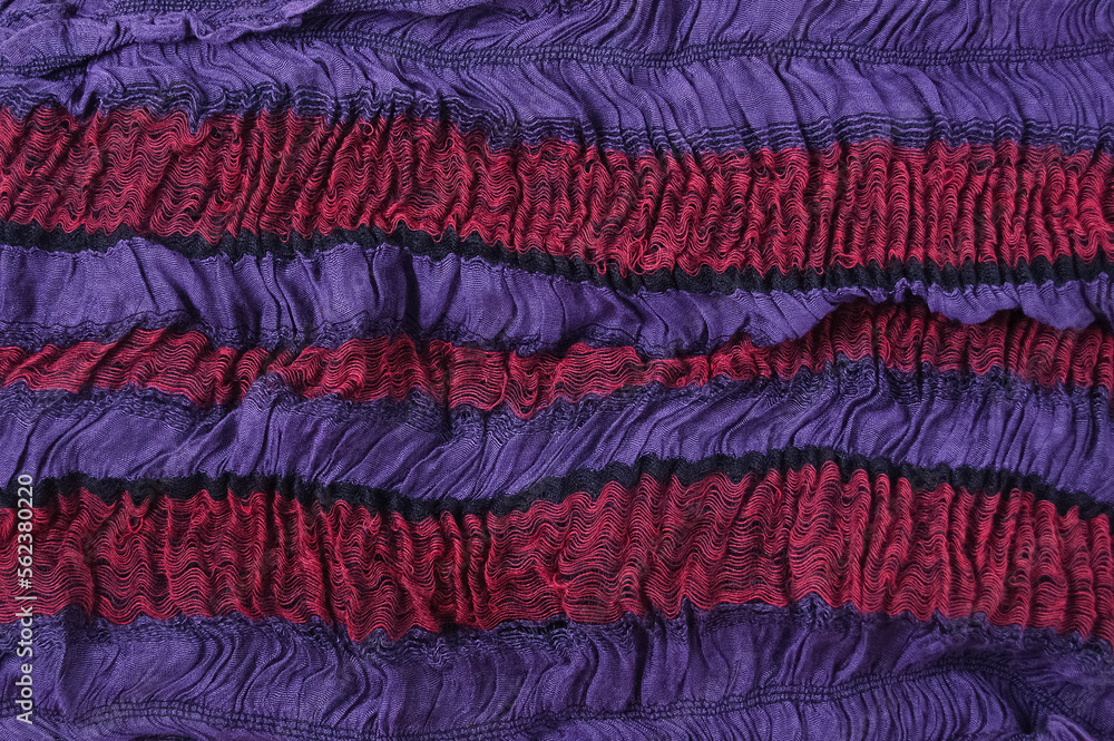 Close-up of a fabric swatch on a purple-red elastic band. Wrinkled fabric, two-tone. Close-up of a fabric swatch on a purple-red elastic band. Wrinkled fabric, two-tone.