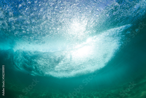 huge powerful wave breaking in the ocean with underwater bubbles and sun rays