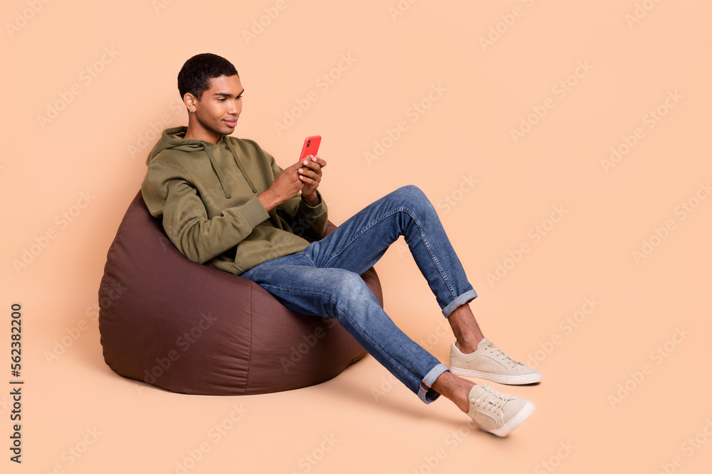 Full length photo of concentrated man hold modern device typing read news share post repost empty space isolated on beige color background Full length photo of concentrated man hold modern device typing read news share post repost empty space isolated on beige color background