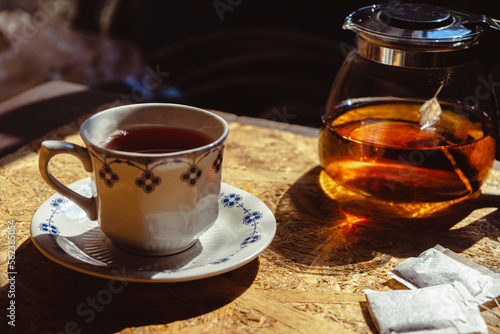 Warm tea with teapot and tea bag on natural wood background