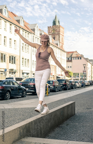 glückliche junge Frau balanciert in der Stadt