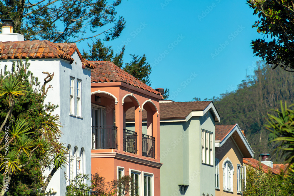 Row of decorative houses red white and green with visible balconies and windows with blue sky background