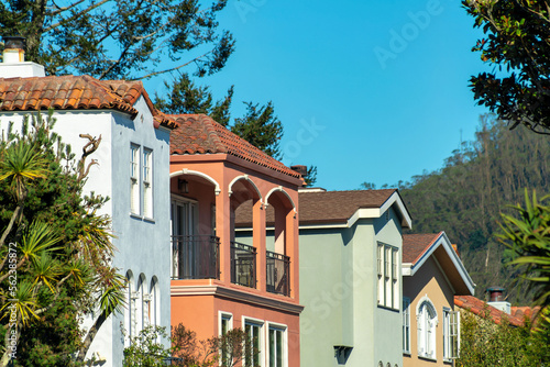 Row of decorative houses red white and green with visible balconies and windows with blue sky background © Aaron