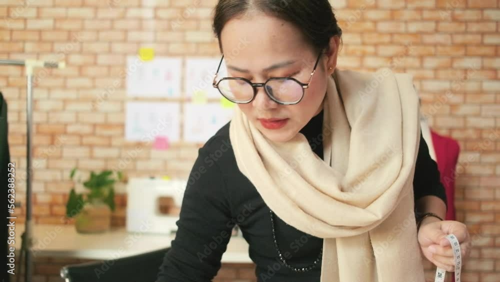 Asian middle-aged female fashion designer works in a studio by ...