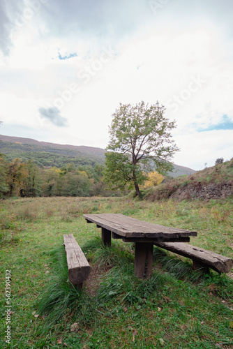 Mesa de picnic de madera para comer en medio de la naturaleza con las increíbles vistas de la montaña con todos sus árboles y las hojas en sus ramas de los colores del invierno.