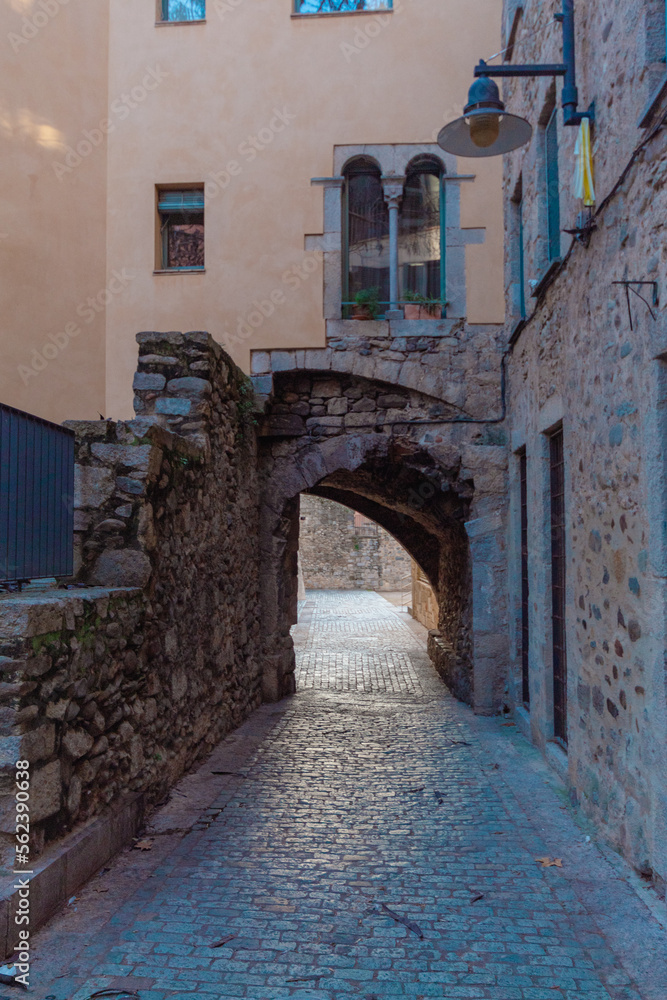 Pequeño paso para cruza por debajo de los estrechos edificios de la ciudad de Gerona con las ventanas finalizadas en arcos.
