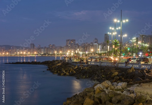 City of Santos, Brazil. Edge of the beach. People sitting on the short wall enjoying the beginning of a summer night.