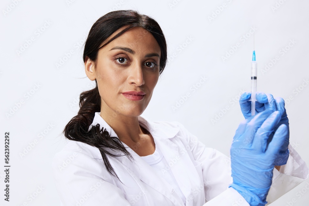 Woman doctor with syringe in hand in medical gown on white background nurse in blue gloves, covid-19 vaccine, shot for pain, concept of health and science Woman doctor with syringe in hand in medical gown on white background nurse in blue gloves, covid-19 vaccine, shot for pain, concept of health and science
