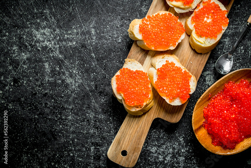 Sandwiches with red caviar on a wooden cutting Board.