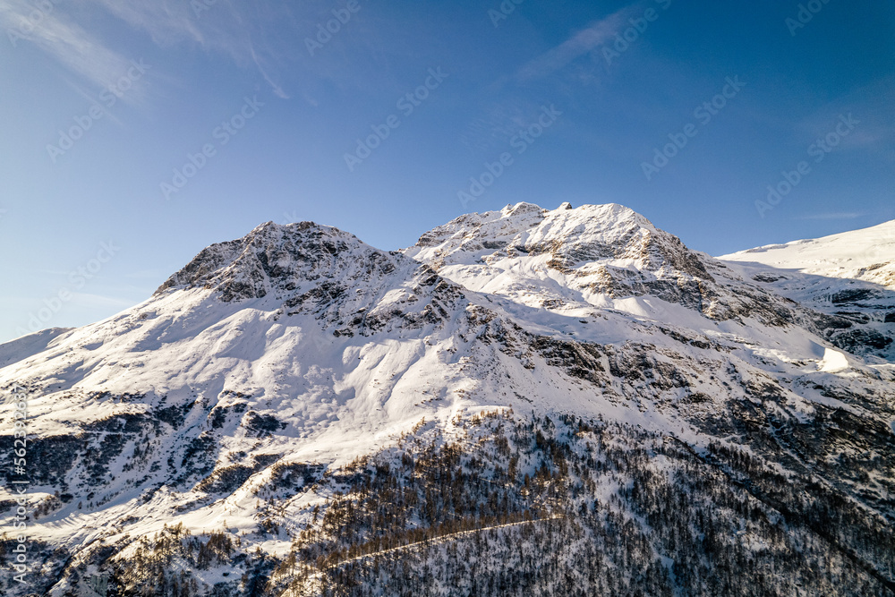 Mountain peak with rocks covered in snow during winter on a sunny day in Switzerland.