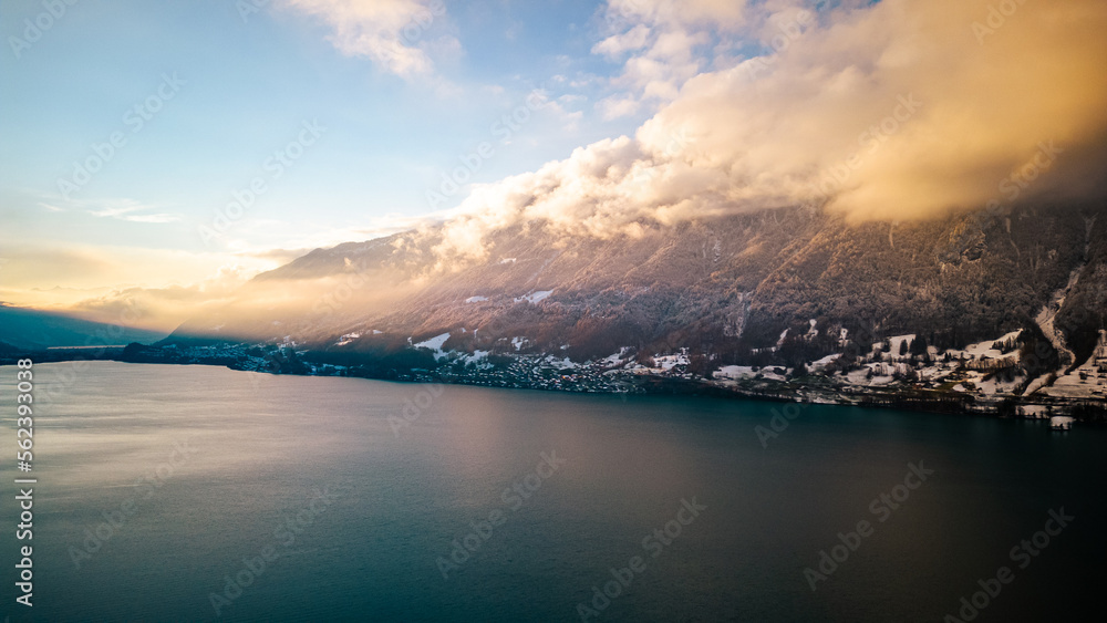 Snow covered mountains around a lake with trees in Switzerland.