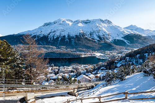 Top view of the lake and town of St. Moritz covered in snow during winter on a sunny day in Switzerland.