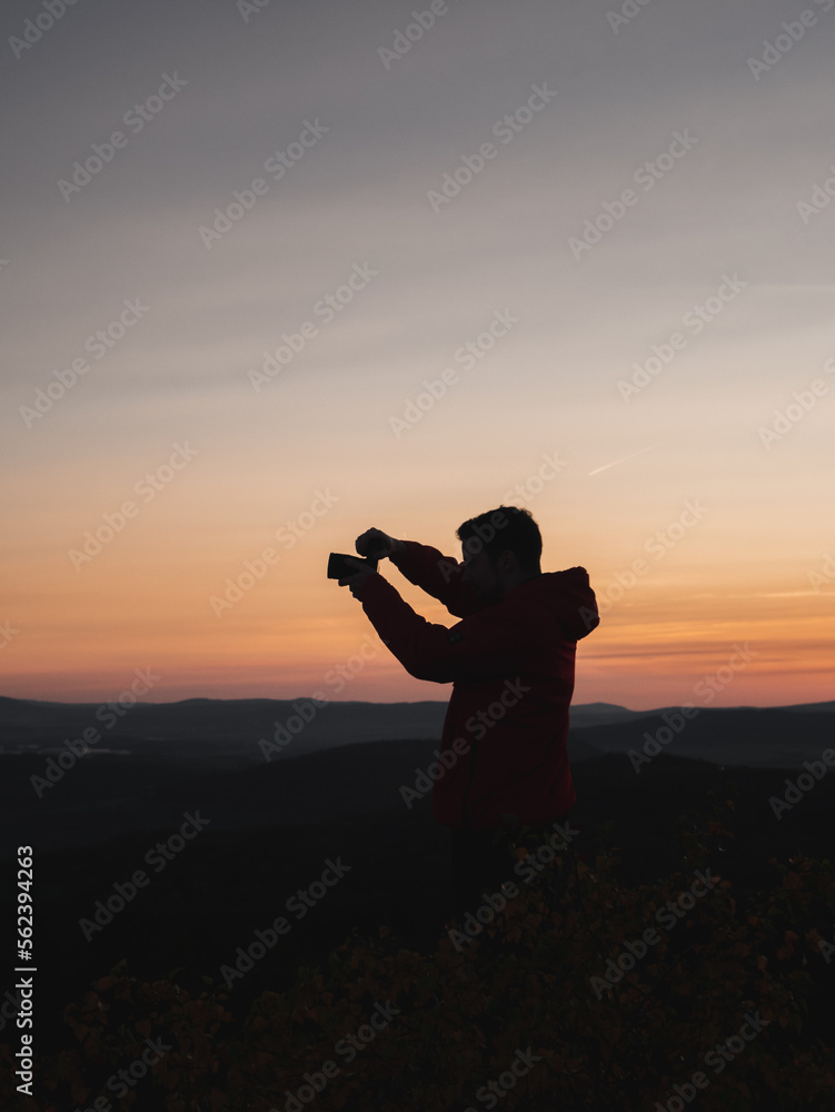 Silhouette of a man photographing the landscape during sunset.