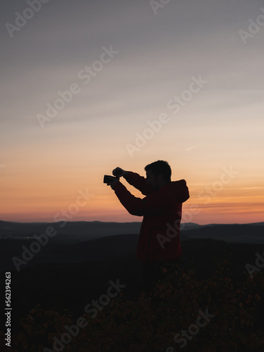 Silhouette of a man photographing the landscape during sunset.
