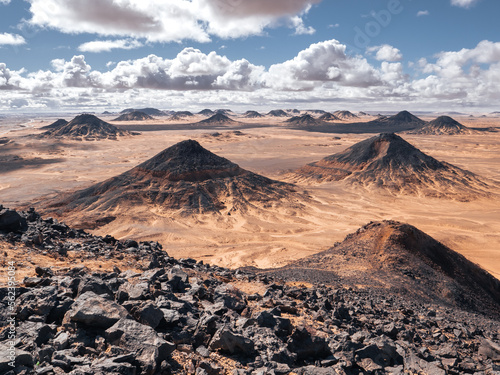 Volcanic hills, rocks and landscape in Black Desert, Egypt on a sunny and cloudy day.