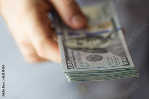 Close-up of a stack of hundred dollar bills in hand blurry