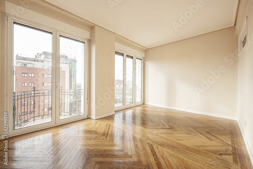 Fotografia, Obraz Empty room with varnished vintage wooden floors, large windows with views and ac