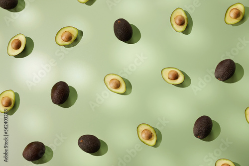 Fresh ripe avocados arranged on green background