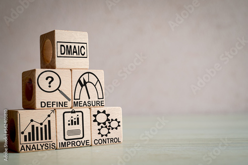 A set of wooden cubes with the word "DMAIC" (Define, Measure, Analyze, Improve, Control) and an icon on wooden cubes with copyspace use for process improvement, Six Sigma, and quality control concept.