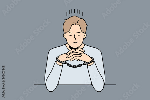 Unhappy young man in handcuffs sit at desk in interrogation room. Stressed male criminal or thief in cuffs wait in jail cell or prison. Vector illustration. 