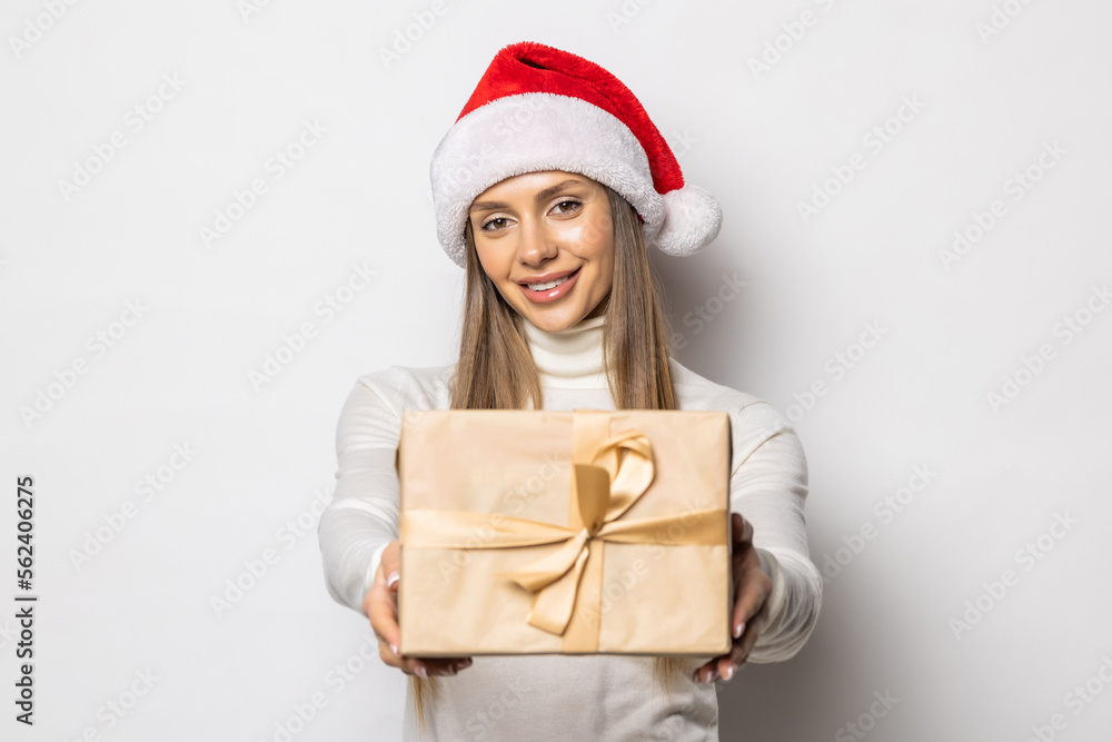 Portrait beautifiul caucasian woman in red Santa hat on white studio background. Christmas New Year holiday concept Surprised Cute girl teeth smiling positive emotions gives big red gift box Portrait beautifiul caucasian woman in red Santa hat on white studio background. Christmas New Year holiday concept Surprised Cute girl teeth smiling positive emotions gives big red gift box