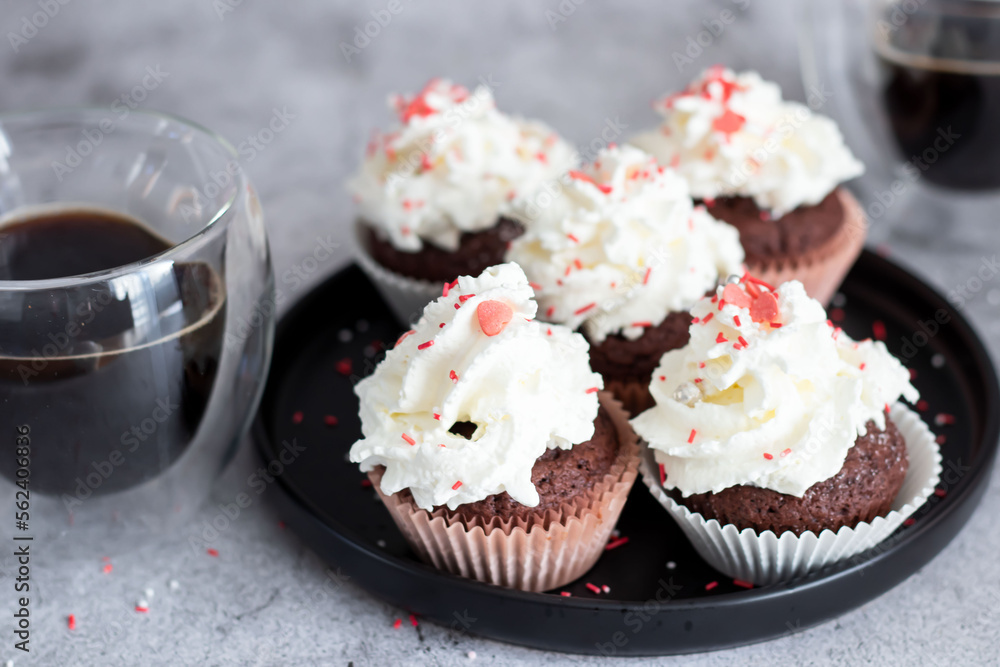 Coffee with muffins, muffins with cream and sprinkles. On a concrete background Coffee with muffins, muffins with cream and sprinkles. On a concrete background